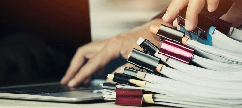 plusieurs reliures de papiers administratif tenus par une main