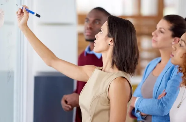 formatrice écrivant sur un tableau avec 3 apprenants qui regardent