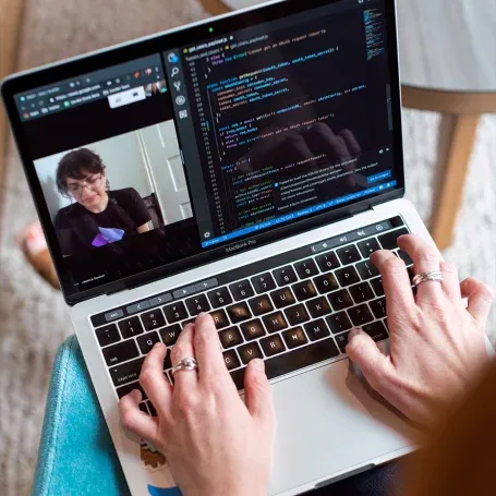 Une personne participant à un appel vidéo sur un ordinateur portable, regardant attentivement l'écran pendant sa formation